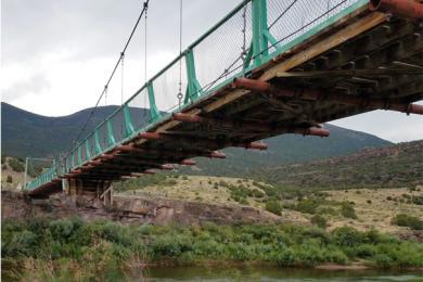 Old bridge with green railings over a river in the Colorado wilderness
